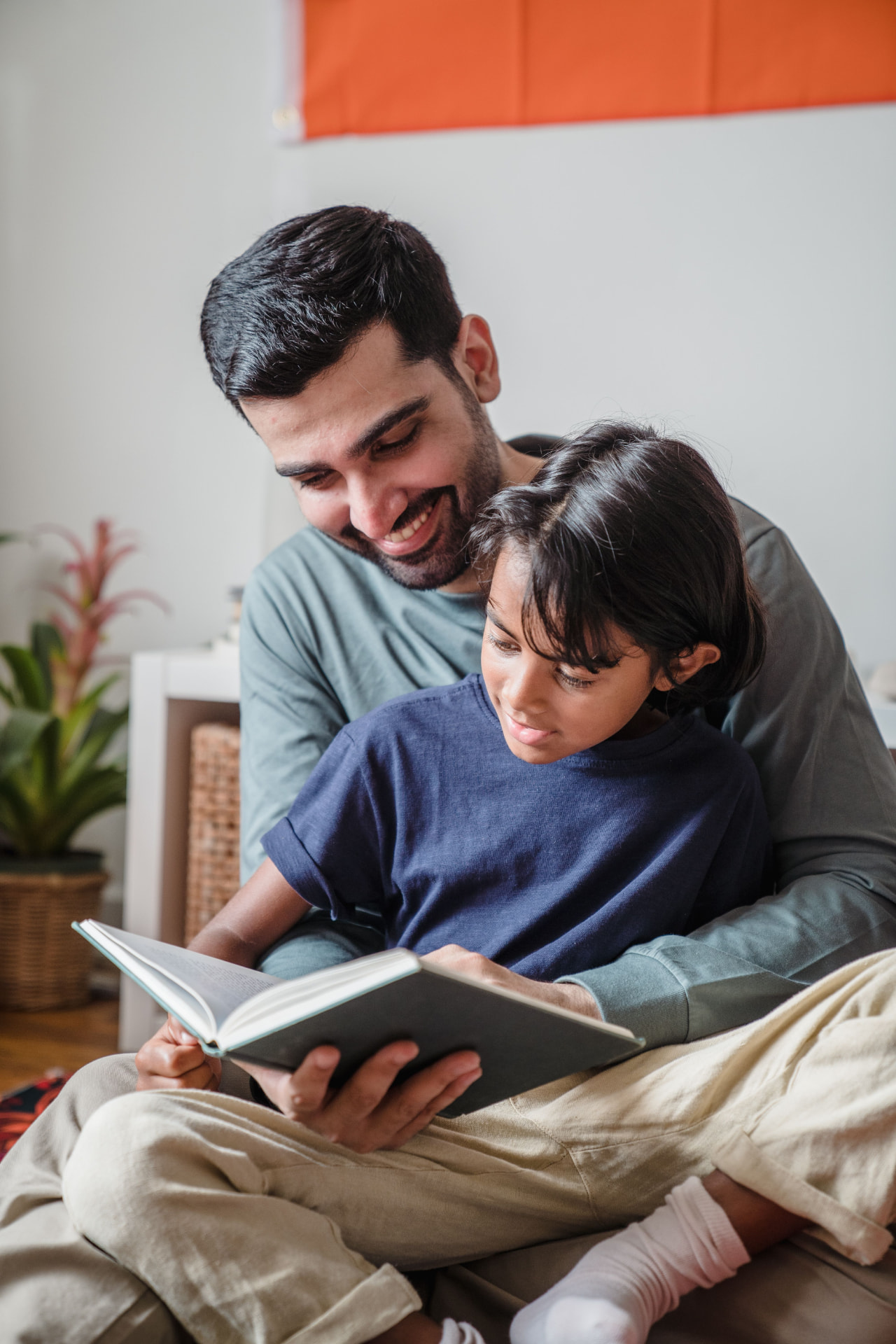 A smiling father and his young son reading a book together